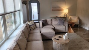 Un salon moderne avec un canapé d’angle, une table basse ronde et un fauteuil.