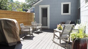 Une terrasse avec des sièges, un barbecue couvert et un pot de fleurs.