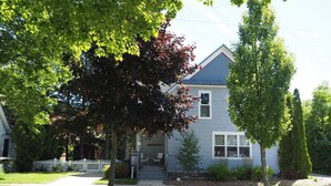 Une maison à deux étages avec un porche à l’avant, une clôture en piquets et une pelouse bien entretenue.
