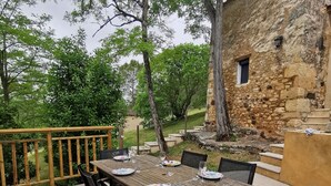 Una zona de menjador a l'aire lliure amb un edifici de pedra al fons.