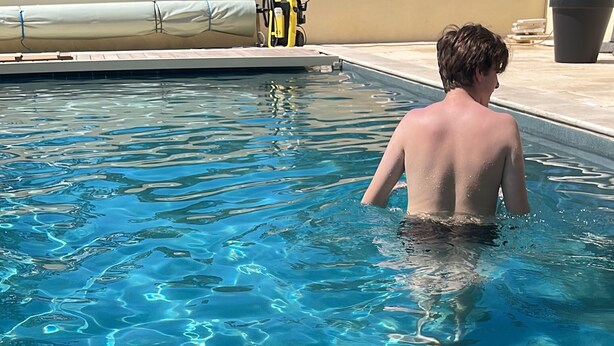 Una piscina amb aigua cristal·lina i una persona banyant-se.