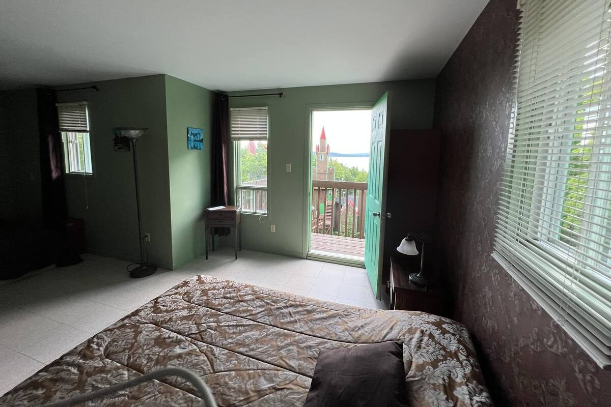 A bedroom with a bed, a desk, and a window with blinds.