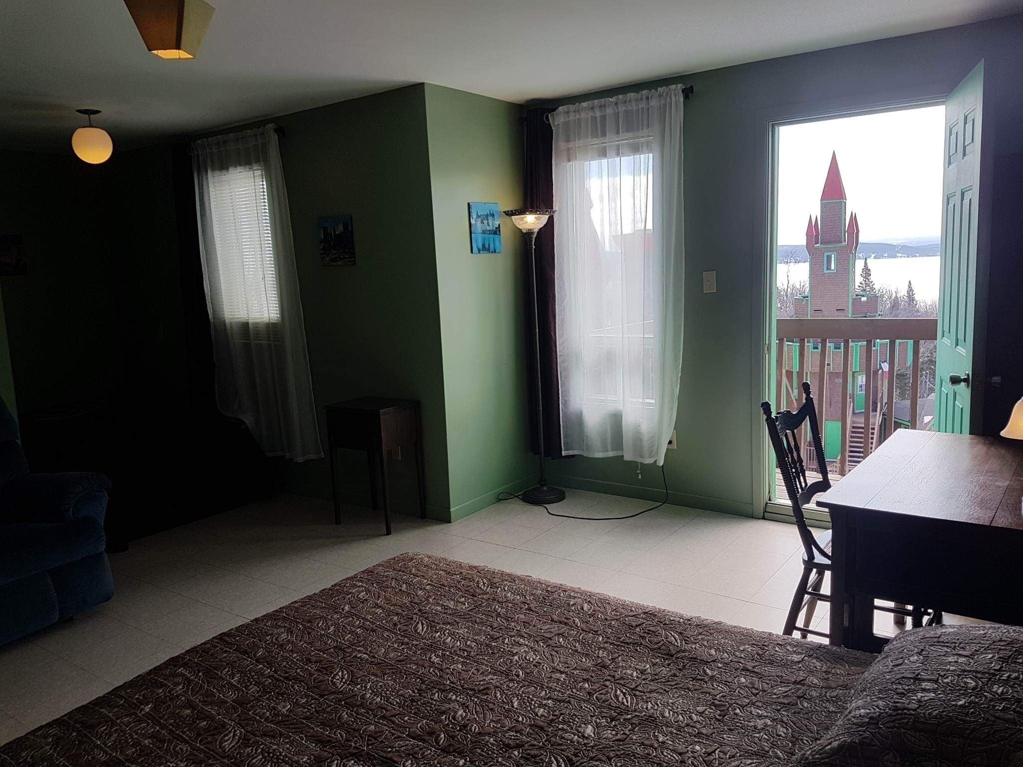 A room with a view of a castle, a dining table, and a lamp.
