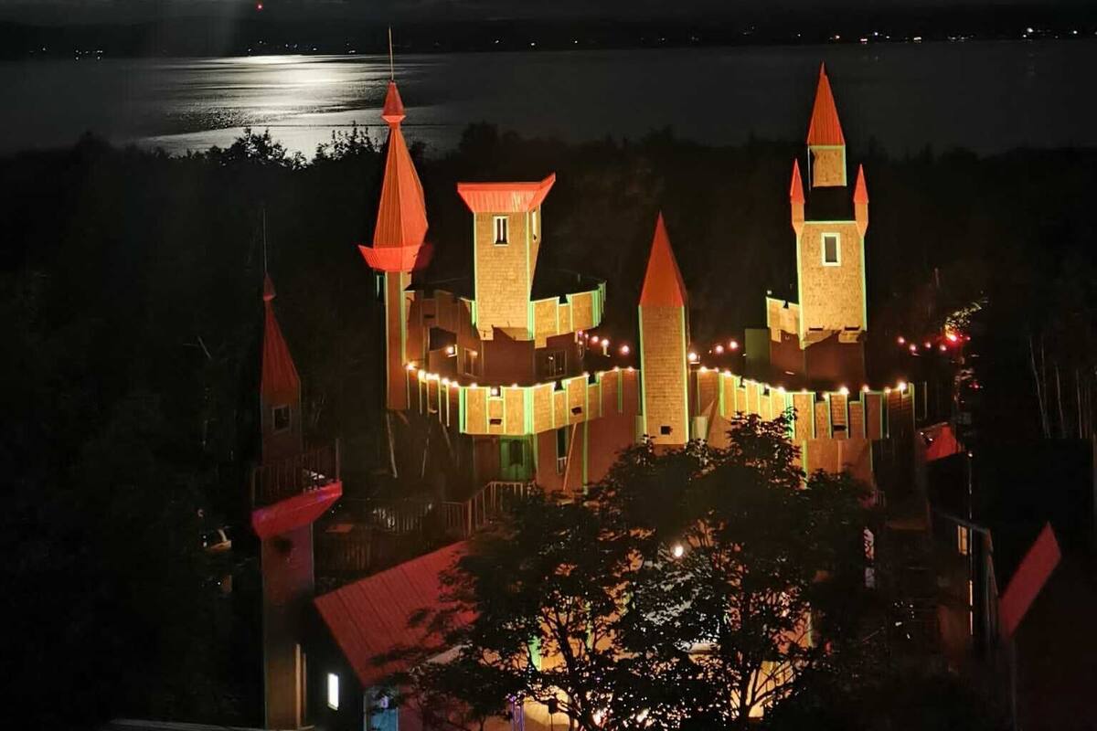 A castle-like structure with multiple towers and a moat, illuminated at night.