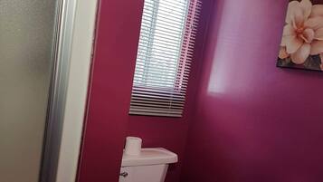 Un baño pequeño con inodoro, lavamanos y ducha.