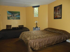 A hotel room with two beds, a window, a lamp, and a painting of a castle. - Auberge Château Bahia (Escuminac)