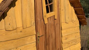 Een houten chalet met schuin dak, een centrale deur met raam, en een klein raam erboven.