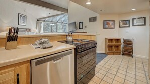 Cocina moderna con lavavajillas, estufa y pileta. Cuenta con alacenas de madera, una encimera y una ventana que proporciona luz natural.