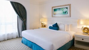 Quarto de hotel com uma cama grande, duas mesas de cabeceira com luminárias, um quadro na parede e uma janela com cortinas.