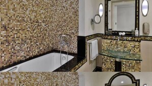 Um banheiro com paredes revestidas de mosaicos, pia de vidro e um espelho grande.