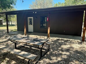 Un petit bâtiment doté d’un patio couvert, d’une table de pique-nique et d’un extincteur fixé au mur.