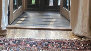 An open glass door leading to a wooden deck with a view of a house and trees. - Studio in upscale, intimate Black Mountain neighborhood (Black Mountain)