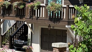 A two-story house with a garage, a staircase, and a balcony with hanging flower baskets. - Studio in upscale, intimate Black Mountain neighborhood (Black Mountain)