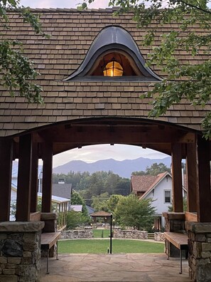 A covered patio area with stone columns, a lantern, and a view of mountains in the background. - Studio in upscale, intimate Black Mountain neighborhood (Black Mountain)