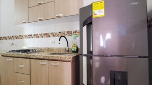 A kitchen with light wood cabinets, a stainless steel refrigerator, a granite countertop, and a tiled backsplash. - Cartagena functional apartment 2 blocks from the beach Marbella (Cartagena de Indias)