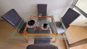 A glass-top dining table with four chairs, a glass of water, and a cup on the table. - Cartagena functional apartment 2 blocks from the beach Marbella (Cartagena de Indias)