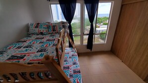 A bedroom with a bed, a wooden headboard, a window with curtains, and a view of the outside. - Cartagena functional apartment 2 blocks from the beach Marbella (Cartagena de Indias)