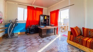 Quarto com escrivaninha, bicicleta ergométrica e sofá com almofadas estampadas.