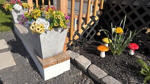 Un jardin avec un parterre de fleurs, une clôture en bois et des décorations en forme de champignons.