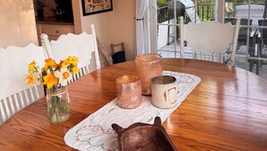 Une table à manger ornée d’un vase de fleurs, d’une carafe et de bougeoirs.