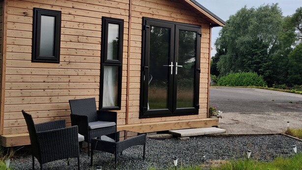Eine Holzhütte mit einer Terrassenanlage, die Korbmöbel und einen Kiesweg zeigt.