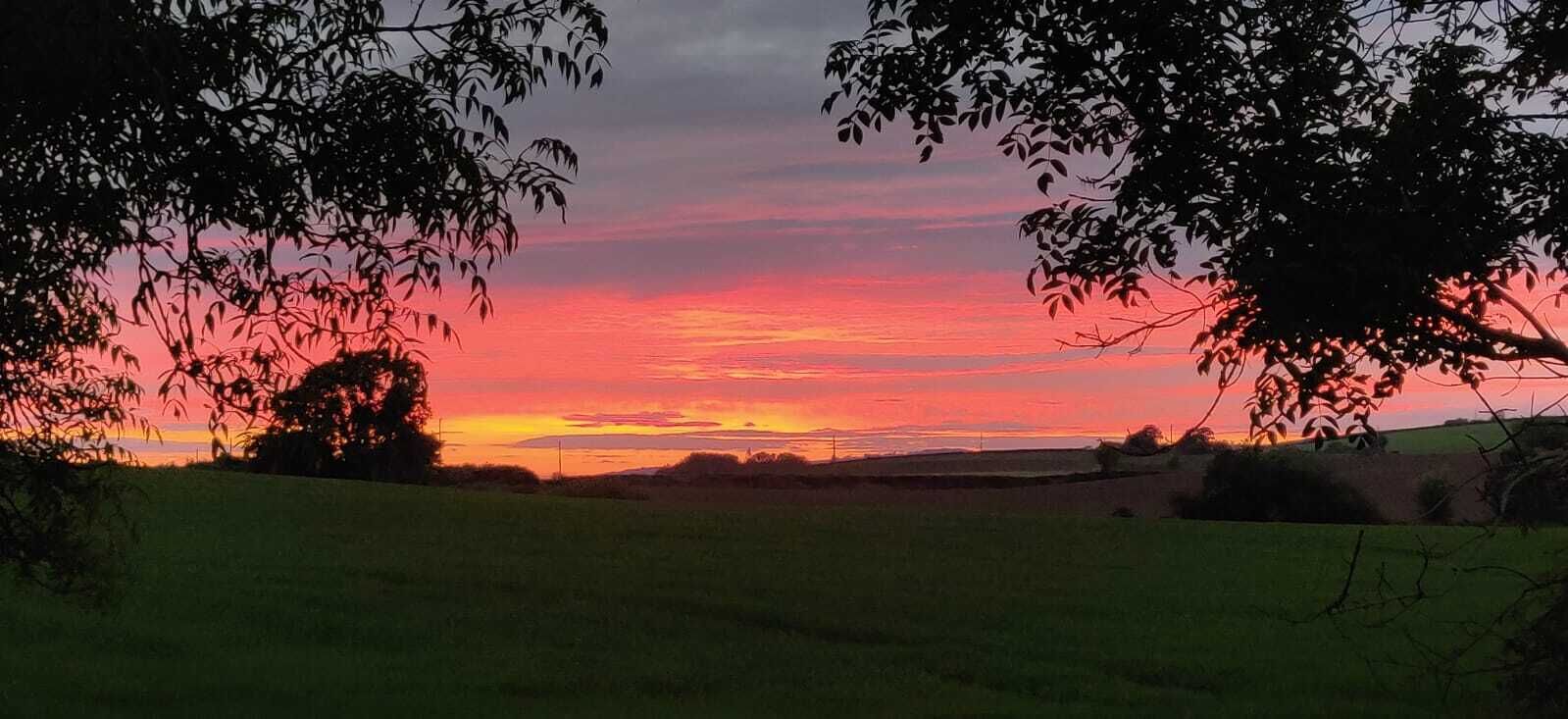 Un atardecer sobre un paisaje rural con campos y árboles.