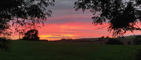 Un atardecer sobre un paisaje rural con campos y árboles.