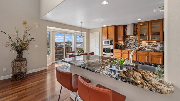 A modern kitchen with a large island, wooden cabinets, and a stone backsplash. - Aurora Manor with Breathtaking Views (Aurora)
