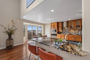 Uma cozinha moderna com uma ilha grande, armários de madeira e painel de pedra.