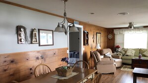 Un comedor con una mesa y sillas de madera, un candelabro y una lámpara fijada a la pared.