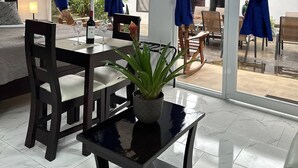 A modern dining area with a table, chairs, and a potted plant. - Hotel Serendipity tortuguero (Colorado)