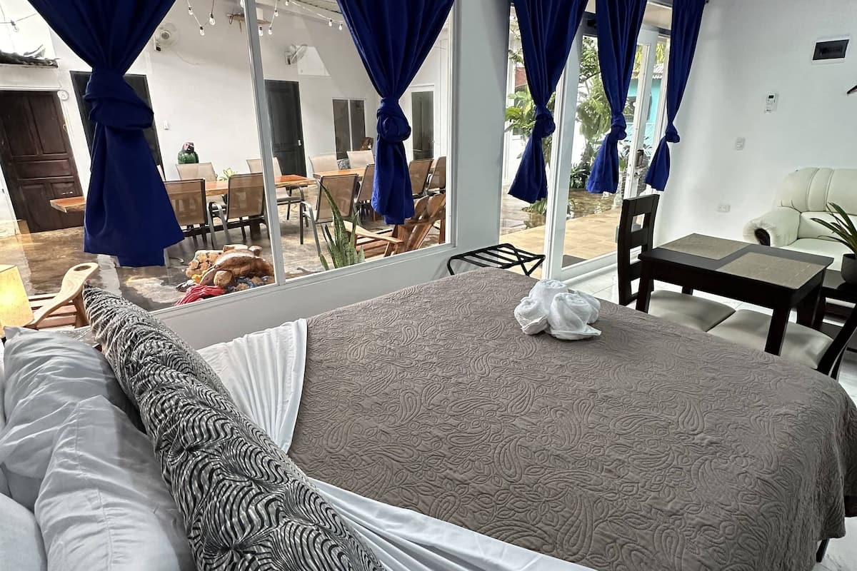 Ein Schlafzimmer mit einem großen Bett, einem Sofa und einem Essbereich, der durch das Fenster sichtbar ist.