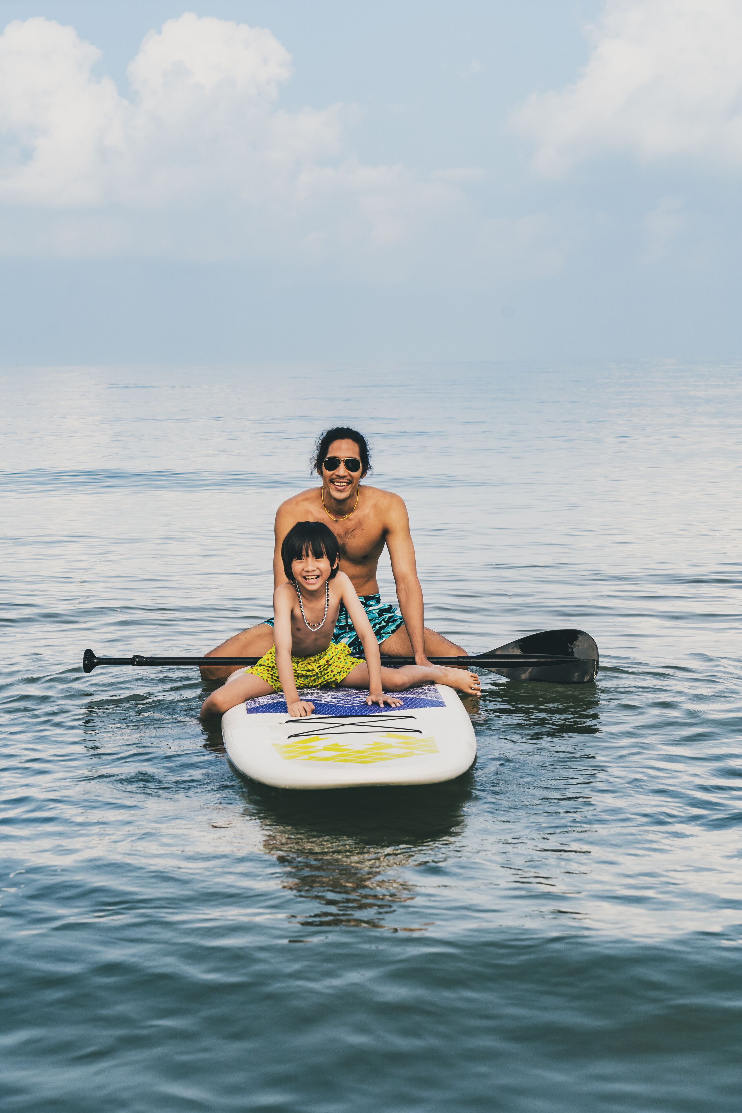 A person sitting on a paddleboard in calm water.