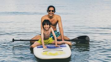 A person sitting on a paddleboard in calm water.