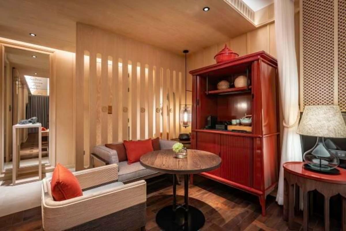 A modern living room with a round wooden table, a red cabinet, and a sofa with cushions.