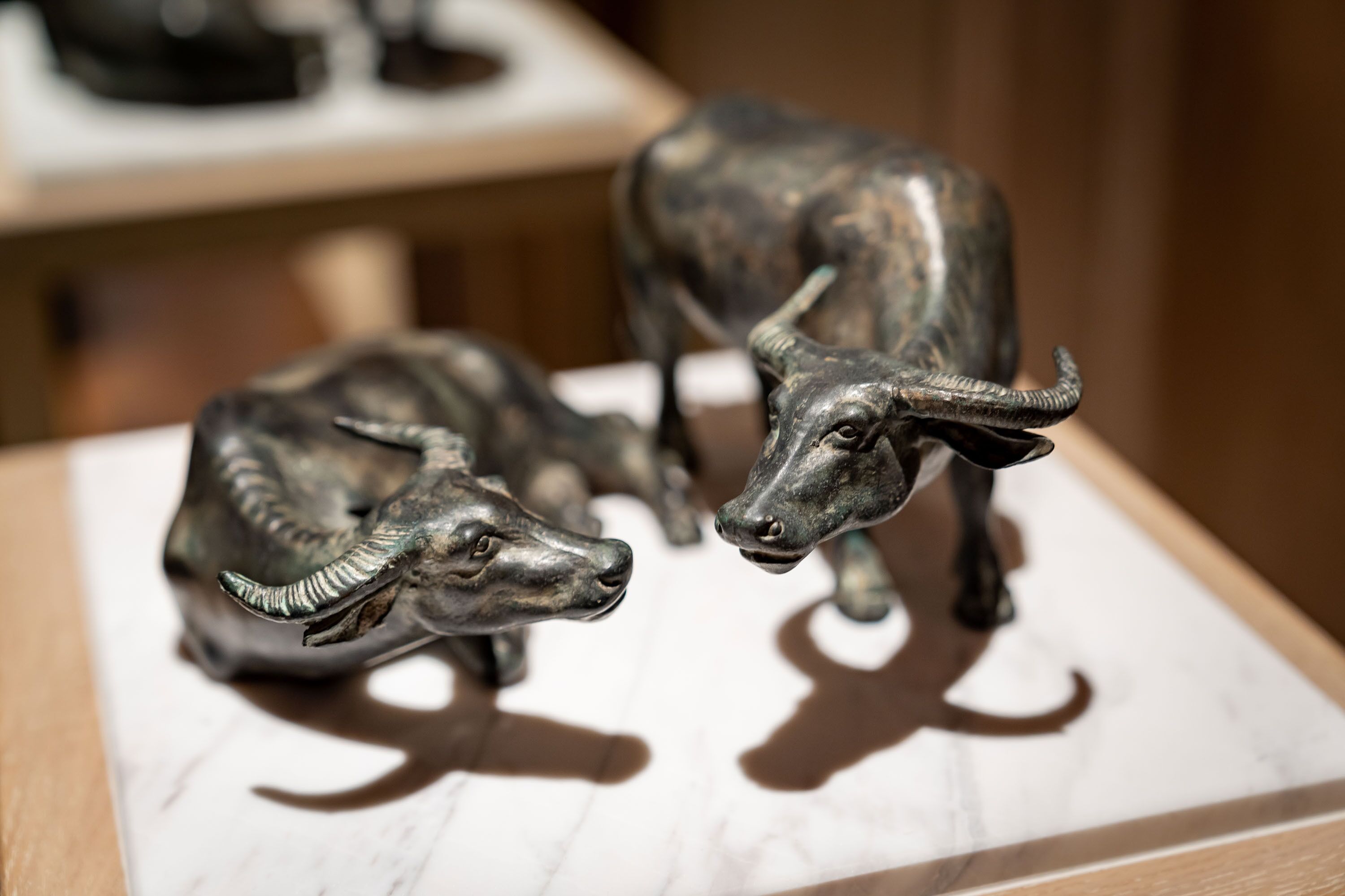 Two metallic bull sculptures on a white marble surface.