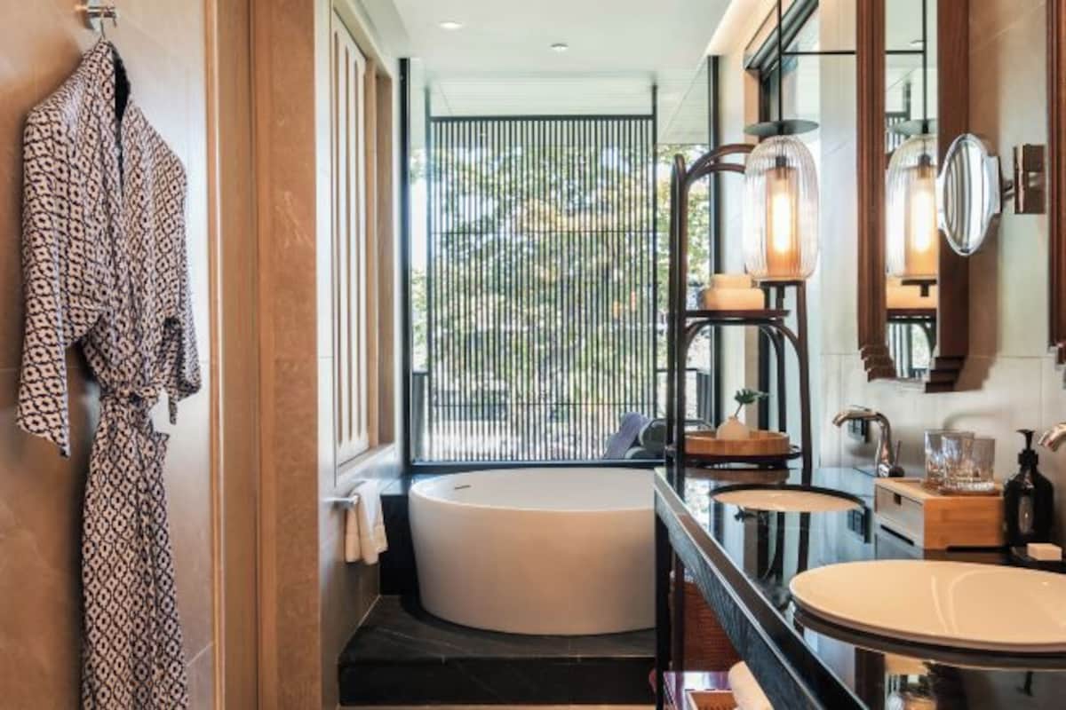 A modern bathroom with a freestanding bathtub, a round vanity with a mirror, and a robe hanging on a rack.