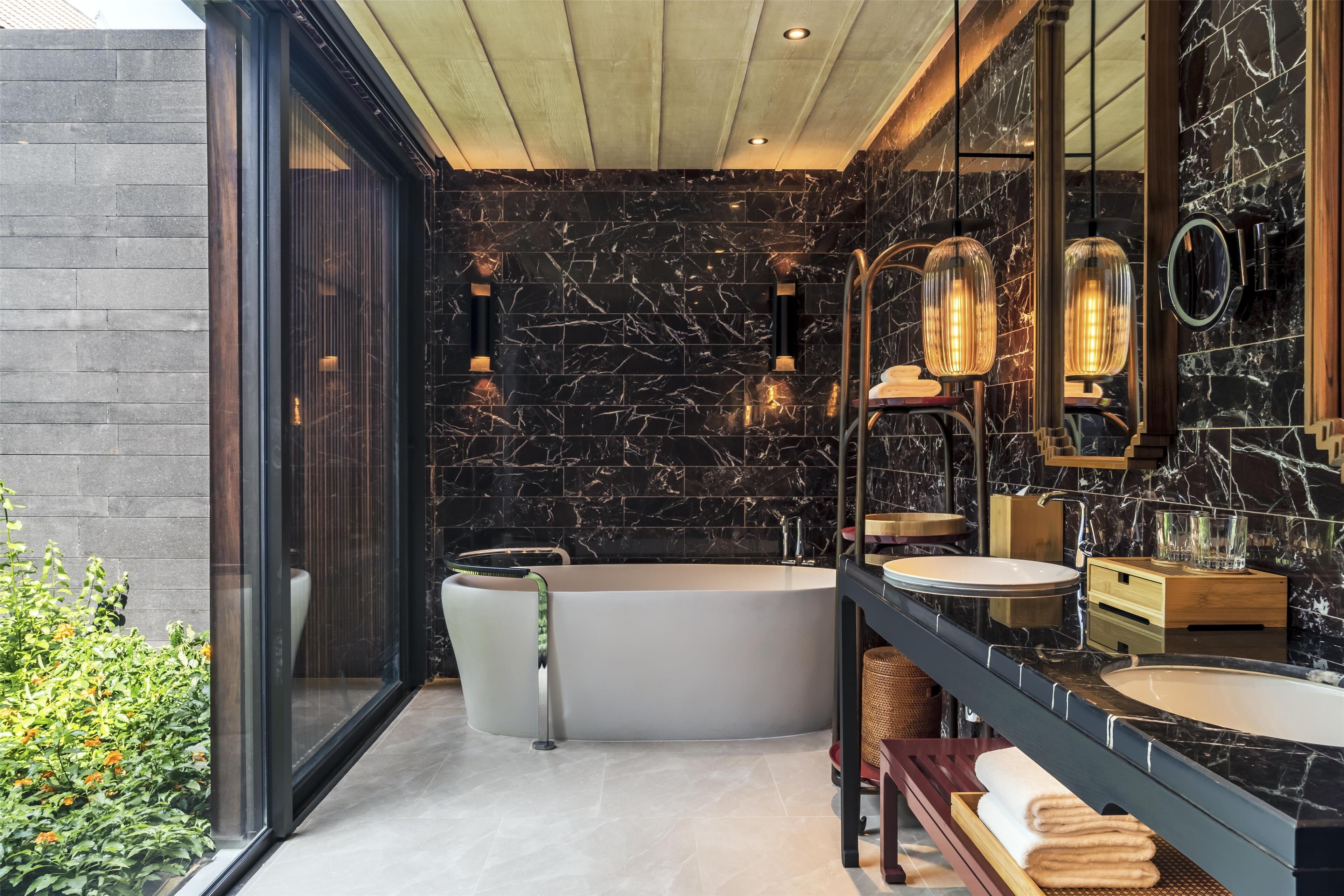 Ein modernes Badezimmer mit einer freistehenden Badewanne, einem großen Spiegel und einem Waschtisch mit Spüle und Arbeitsplatte.