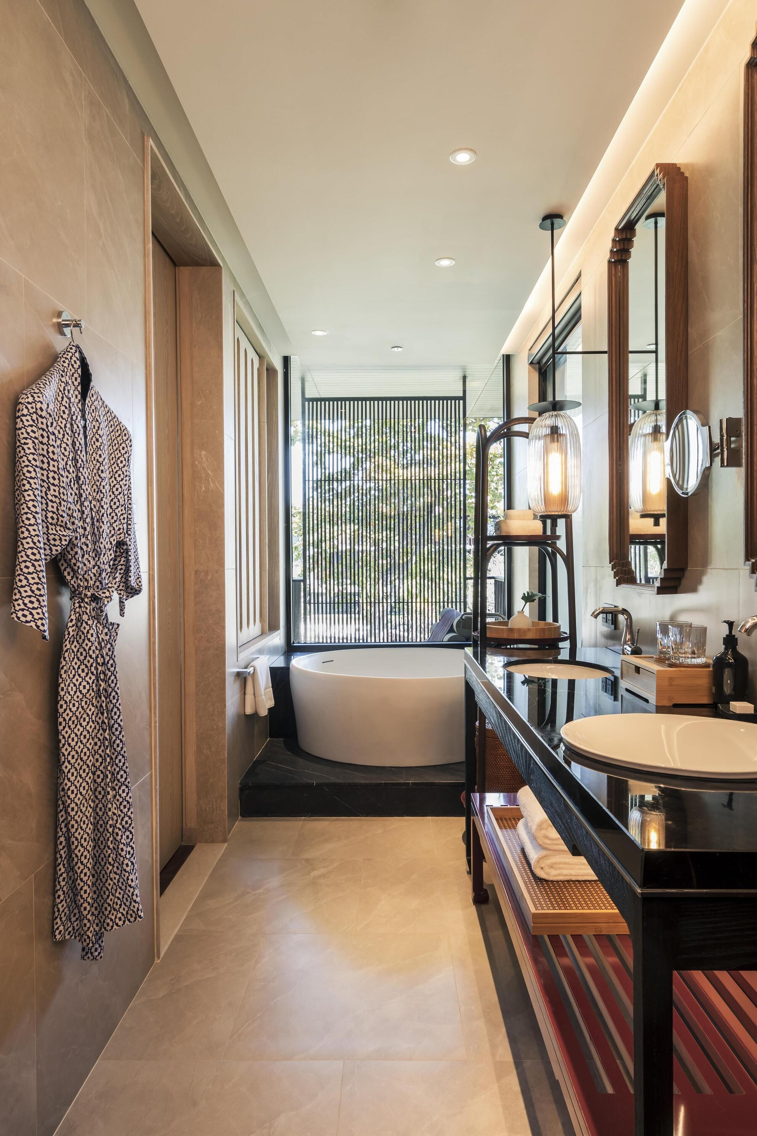 A modern bathroom with a bathtub, a large mirror, and a vanity with a sink.