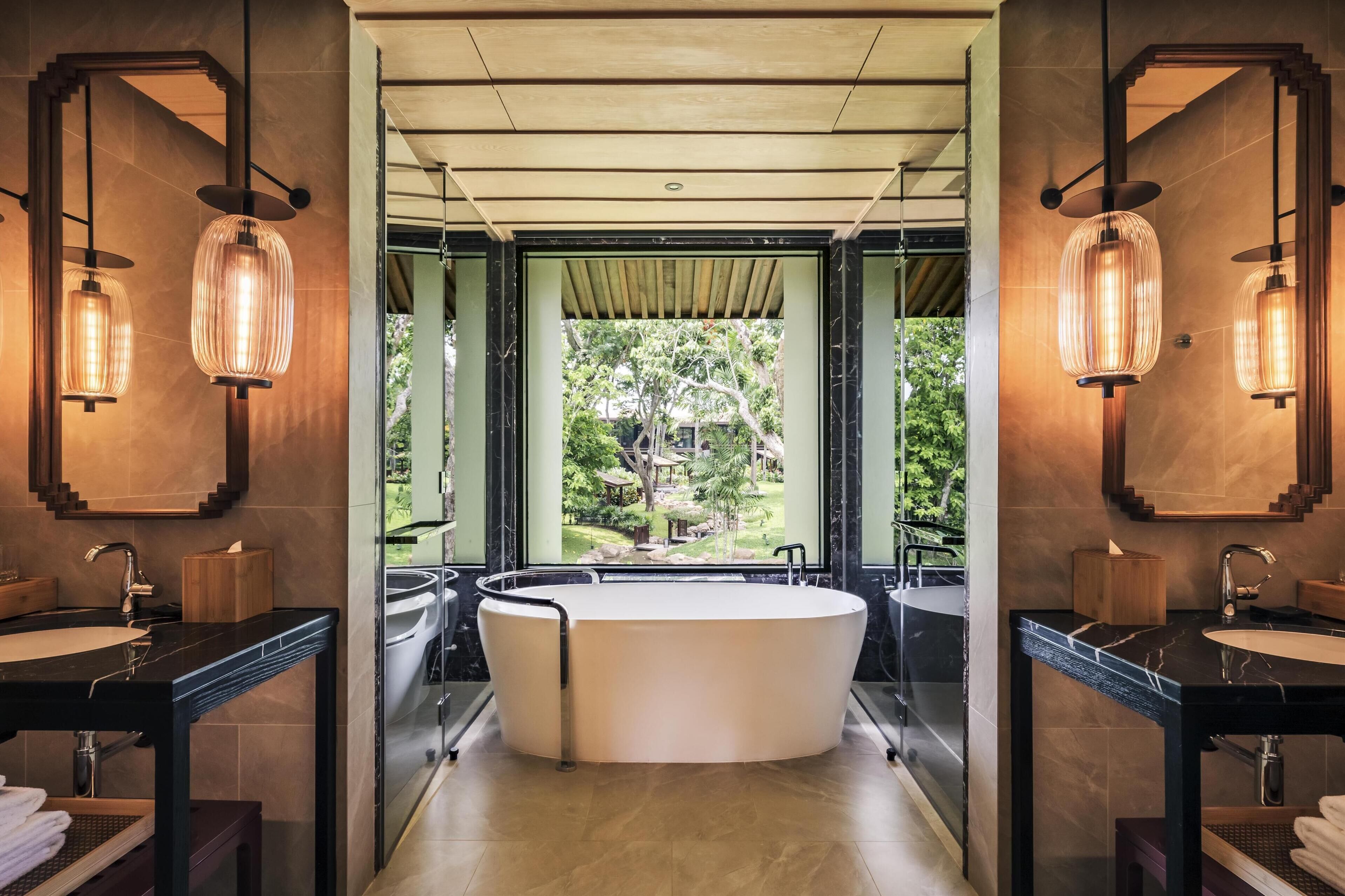 Une salle de bain moderne avec une baignoire sur pieds, deux vasques et de grands miroirs.