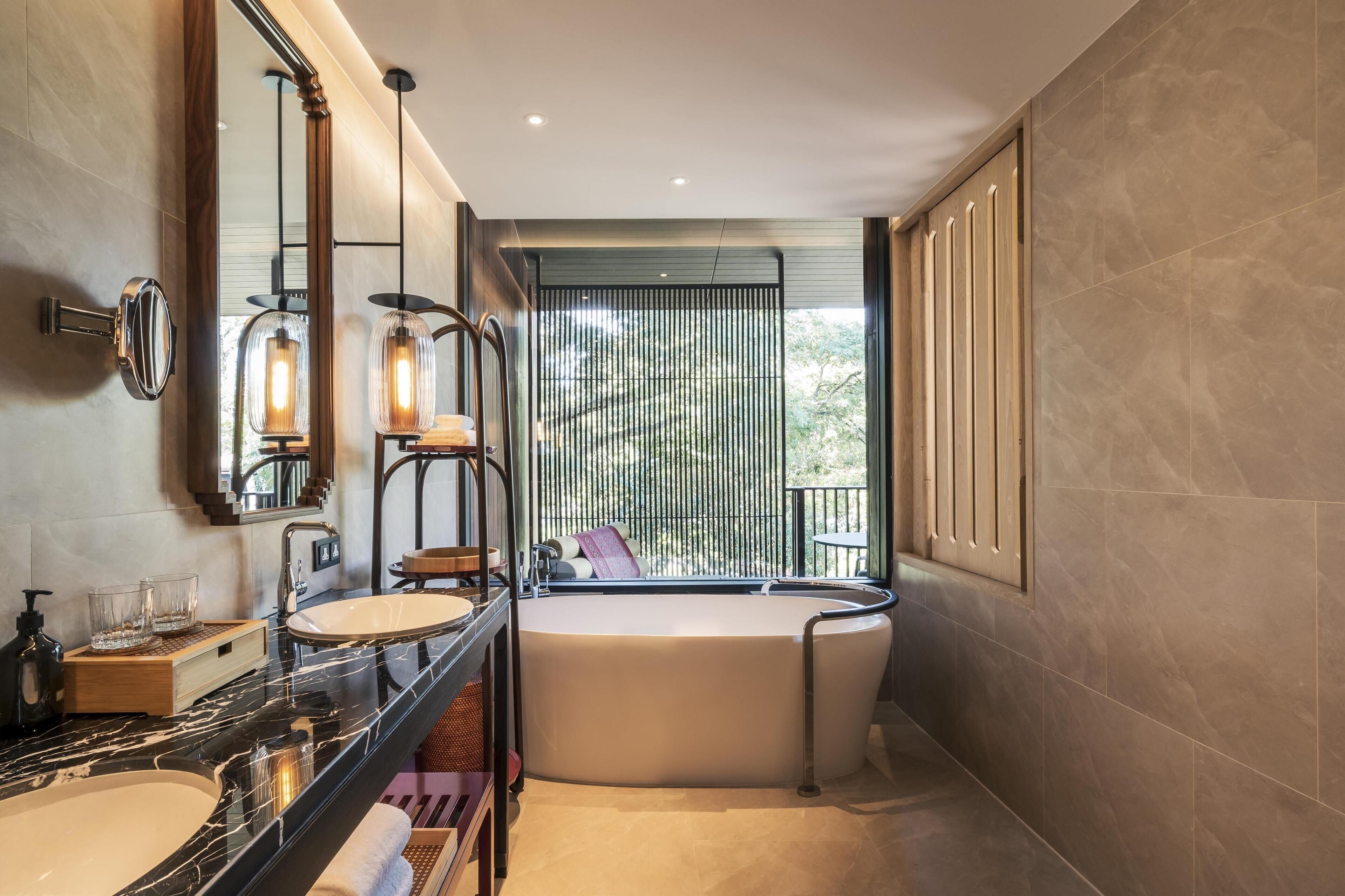 Une salle de bain moderne avec une grande baignoire, deux lavabos et un grand miroir.
