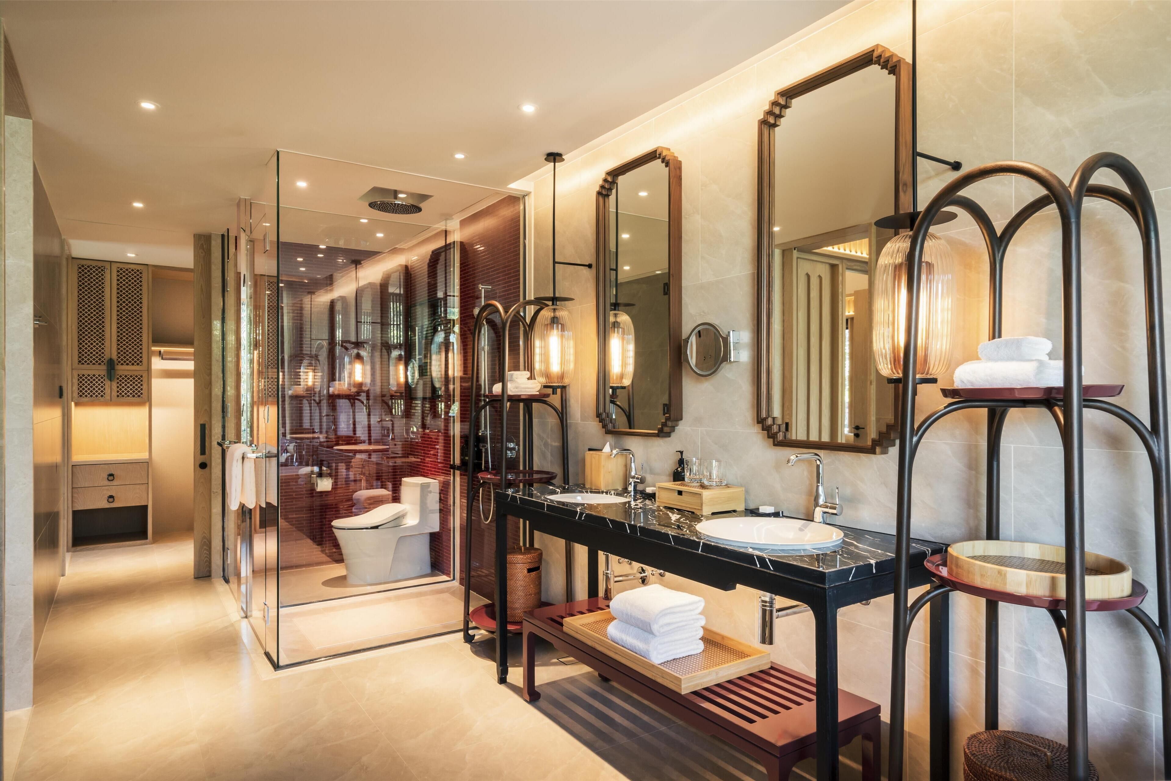 A modern bathroom with a glass-enclosed shower, a vanity with a black countertop, and multiple mirrors.
