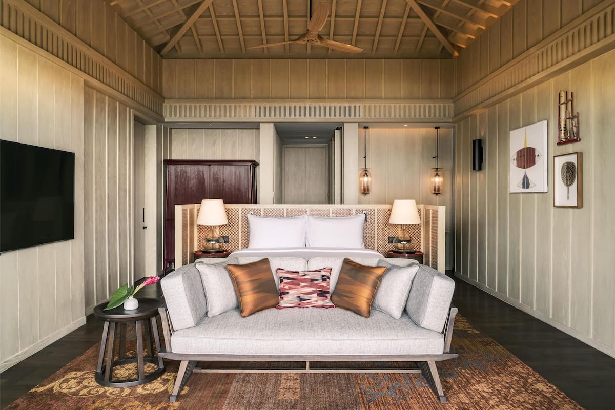 Une chambre d’hôtel avec un grand lit, deux tables de chevet avec des lampes, un téléviseur à écran plat et un tapis décoratif.