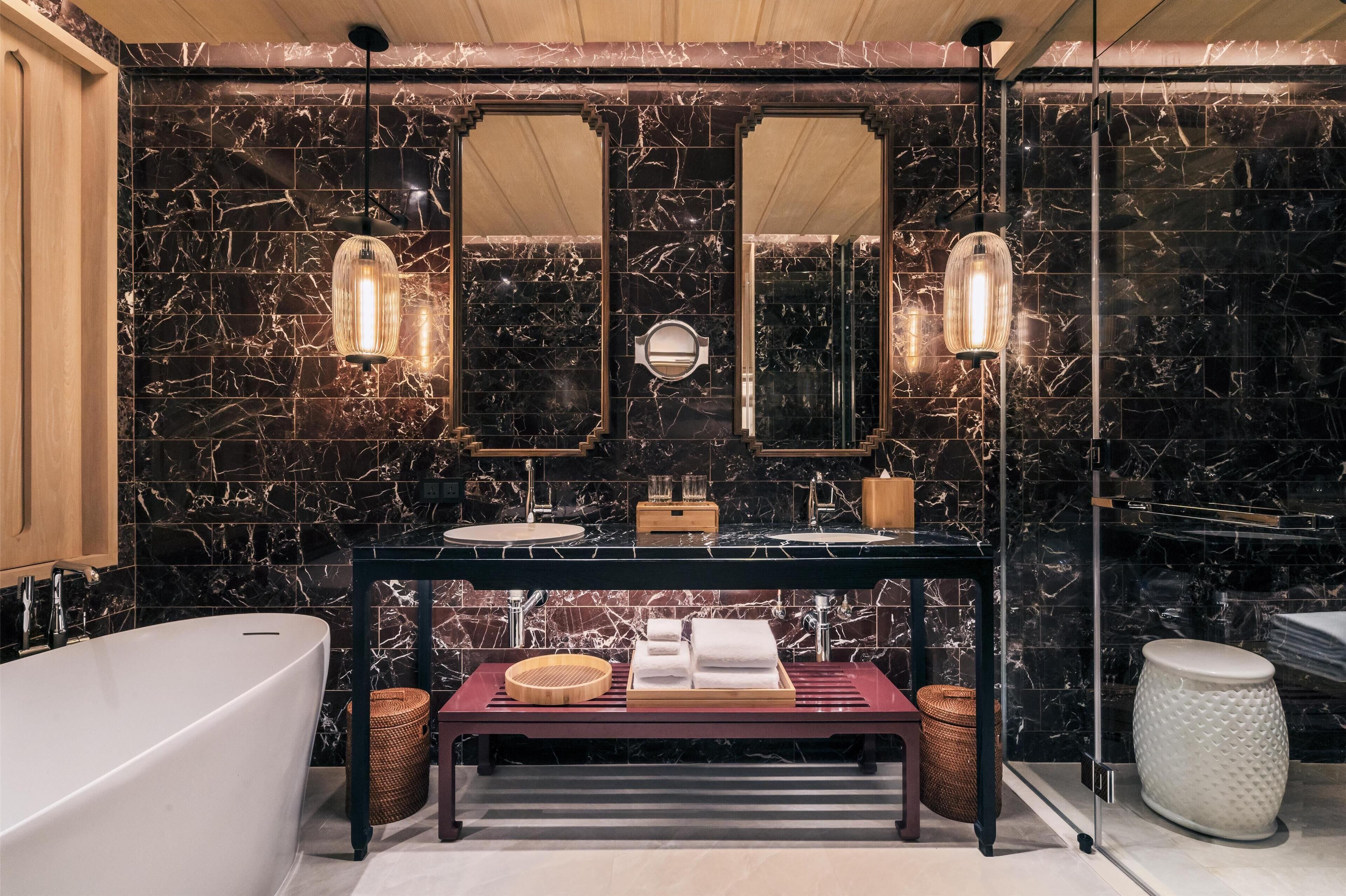 A modern bathroom with a freestanding bathtub, a vanity with a mirror, and a marble backsplash.