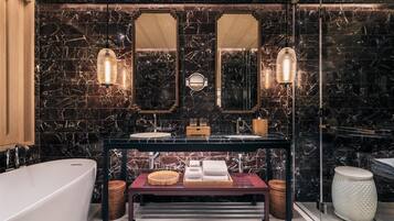 A modern bathroom with a freestanding bathtub, a vanity with a mirror, and a marble backsplash.