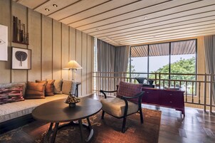 A modern living room with a sofa, armchair, round table, and a view through large windows.