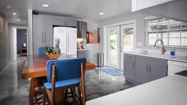 A modern kitchen with grey cabinets, a wooden dining table, and blue chairs.