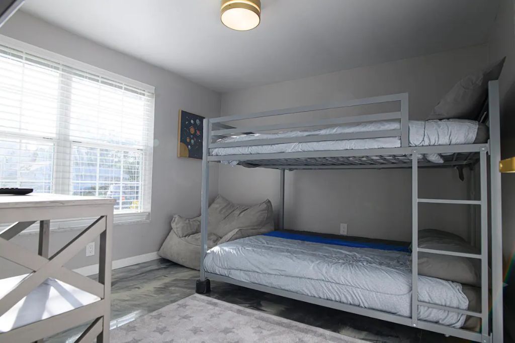 A bunk bed room with a desk and a window.