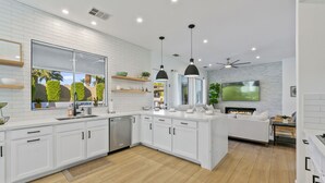 A modern kitchen with white cabinetry, a built-in oven, and a large island with a sink. - The Montage: Luxury Resort Desert Retreat (Indio)