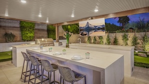 A modern kitchen with a large island, bar stools, and a grill. - The Montage: Luxury Resort Desert Retreat (Indio)
